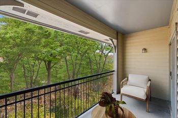 A balcony with a chair and a view of the woods